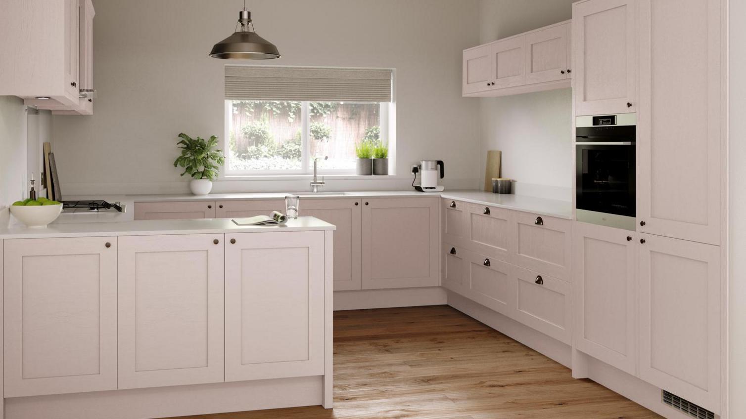A blossom-coloured pink peninsula kitchen from Howdens