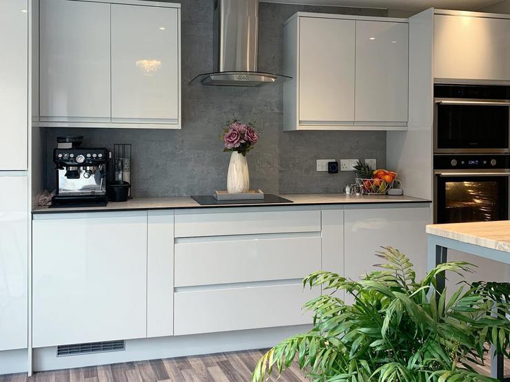 White single wall kitchen idea with integrated handle cupboards, a grey worktop, induction hob and integrated appliances.