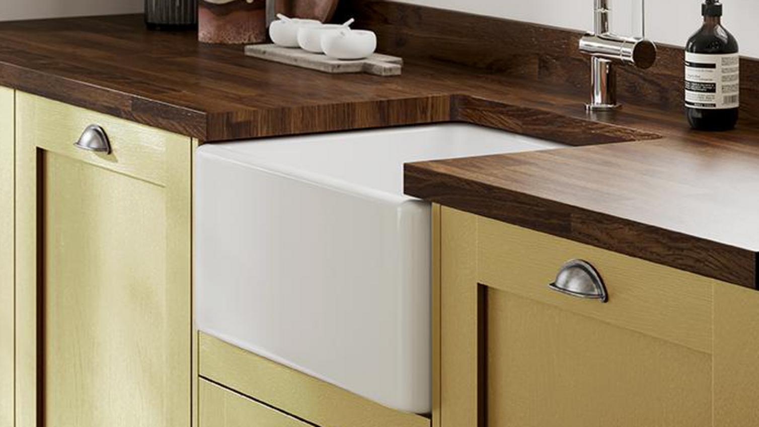 A mustard yellow kitchen using Chilcomb Paintable, styled with wooden worktops, a ceramic sink and cabinet cup handles.