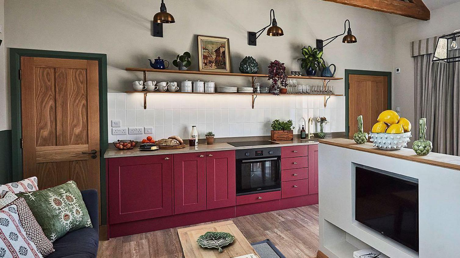 Wine red kitchen design in a single wall layout, with wooden beams, a wooden worktop, an open plan living room.
