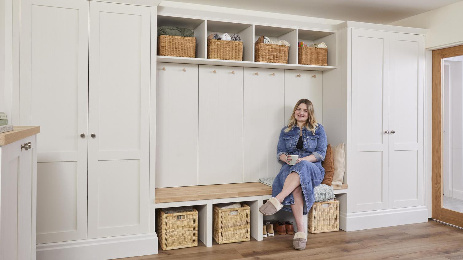 Courtney sat holding a mug, on the bench section of her white, built in storage from Howdens