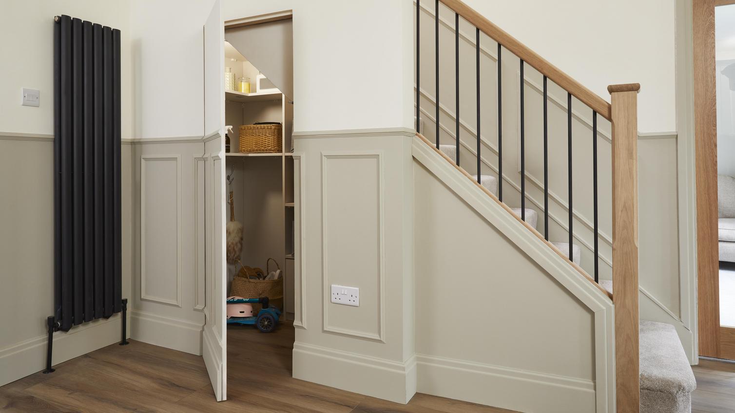 The under-stair storage area with the door ajar, decorated with panelling.