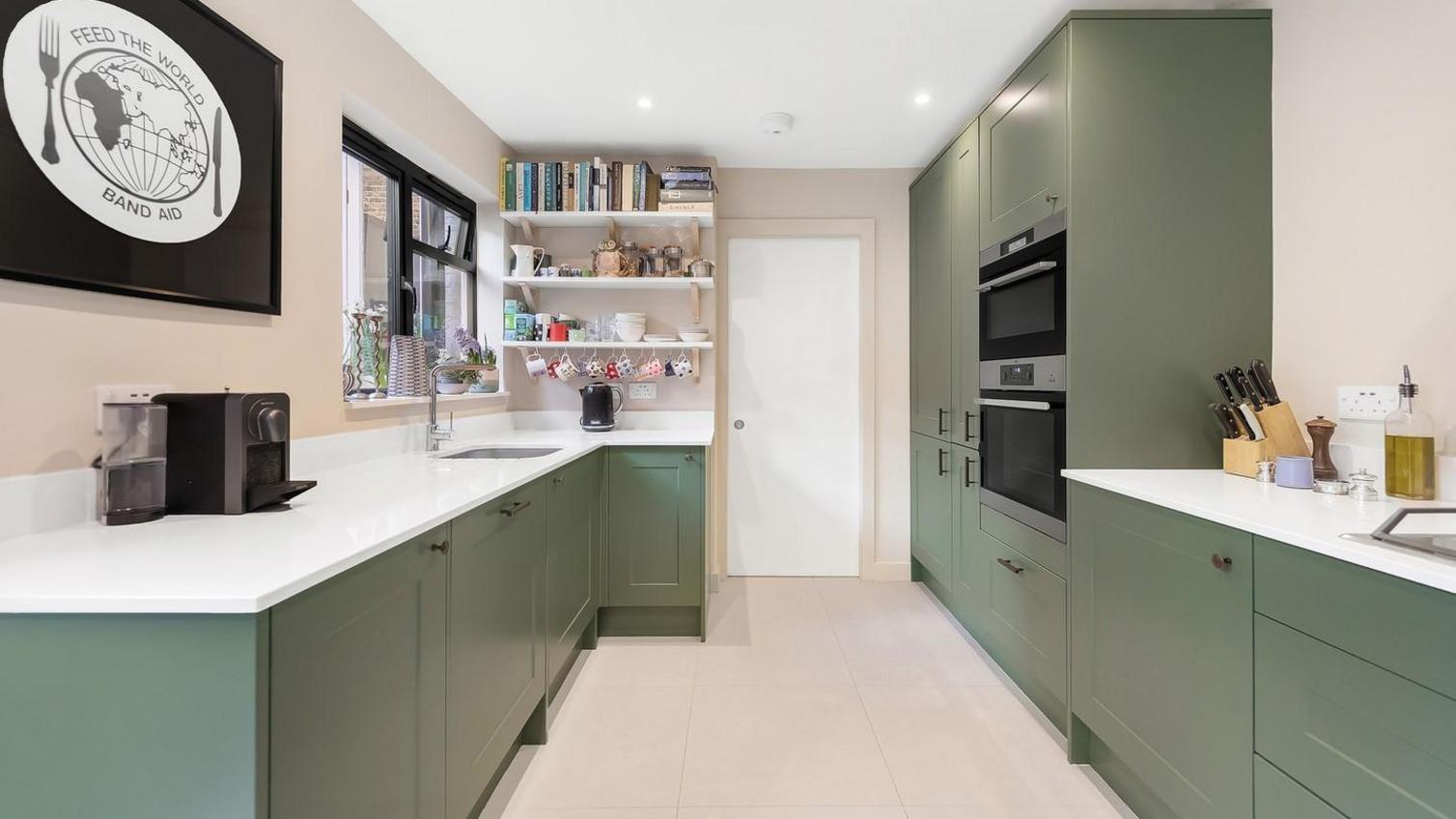 Bespoke worktop idea featuring white worktops paired with green, shaker cupboards in a galley layout.