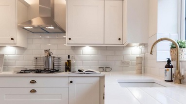 Bespoke worktop idea using white worktops, white shaker cupboards, and aged-brass cup and knob handles.