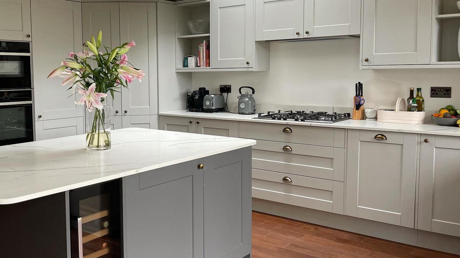 Light and dark grey kitchen design with shaker doors, silver cup and knob handles, white marble worktops.