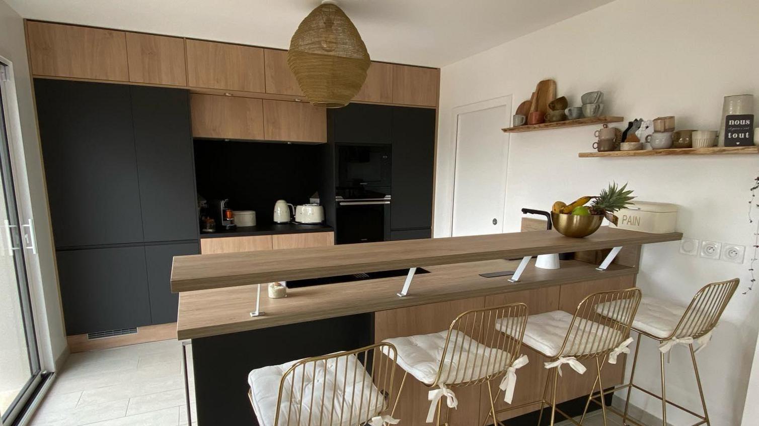 A black integrated handle kitchen with oak units, oak worktops and stone flooring.