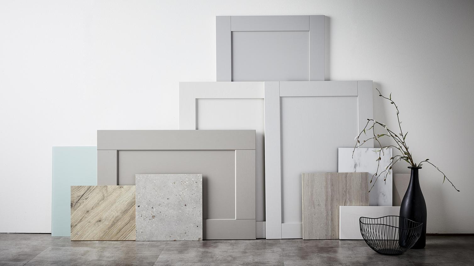 Calm haven flat lay showing a textured stone slab, light oak panels and shaker door fronts in tonal grey shades..