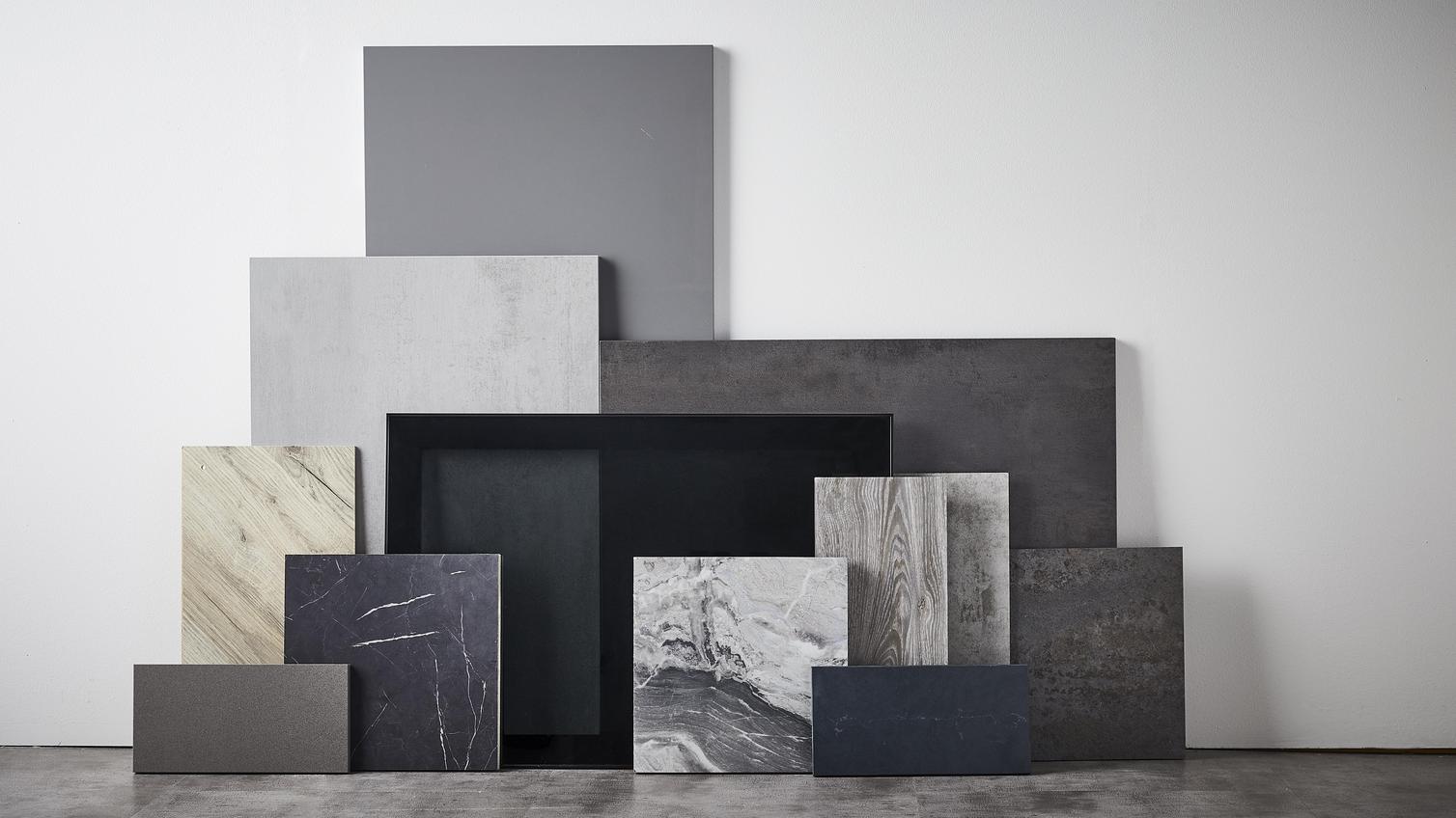 Sensory delight flat lay showing different square and rectangular slabs of textured stone, marble, and black materials.