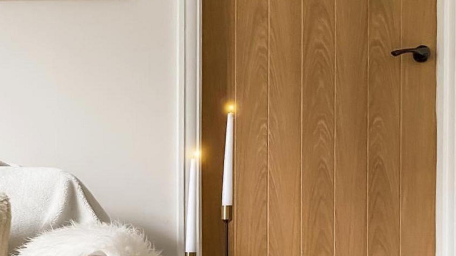 Budget living room idea using black door handles for an on-trend look. Includes an oak door, cream sofa, and white carpet.