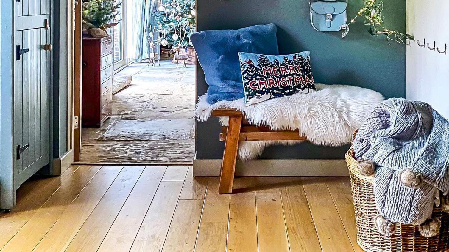 Traditional living room idea using an oak door. Contains oak beams, oak floors, black coat hooks, and a green feature wall.