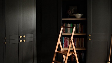 Bespoke living room idea featuring custom storage made from black shaker doors. Has brass handles and for an industrial look.