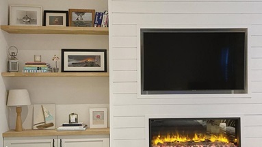 Simple living room idea using open shelving made from oak worktop offcuts. Has white shaker storage units and timber floors.