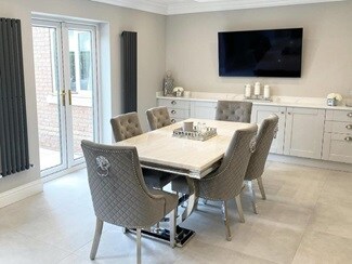 Grey dining room idea with a white table, grey velvet chairs, white tile floors, and light grey shaker base cupboards.