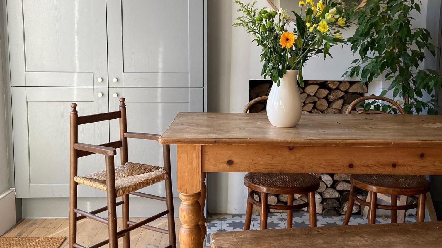 Farmhouse dining room idea with a light grey tower cupboard, a dark solid wood dining table, bench and stool chair.