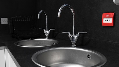 Two, twin stainless-steel sinks and taps set in a black worktop