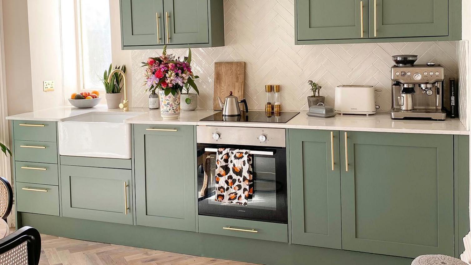 Small single wall shaker kitchen, painted in a green colour and finished with brass-effect bar handles.