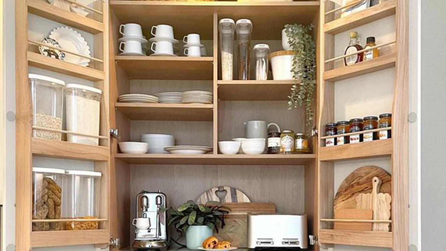 Larder cabinet in a small shaker kitchen, fitted with wood-effect accessories inside to organise storage.