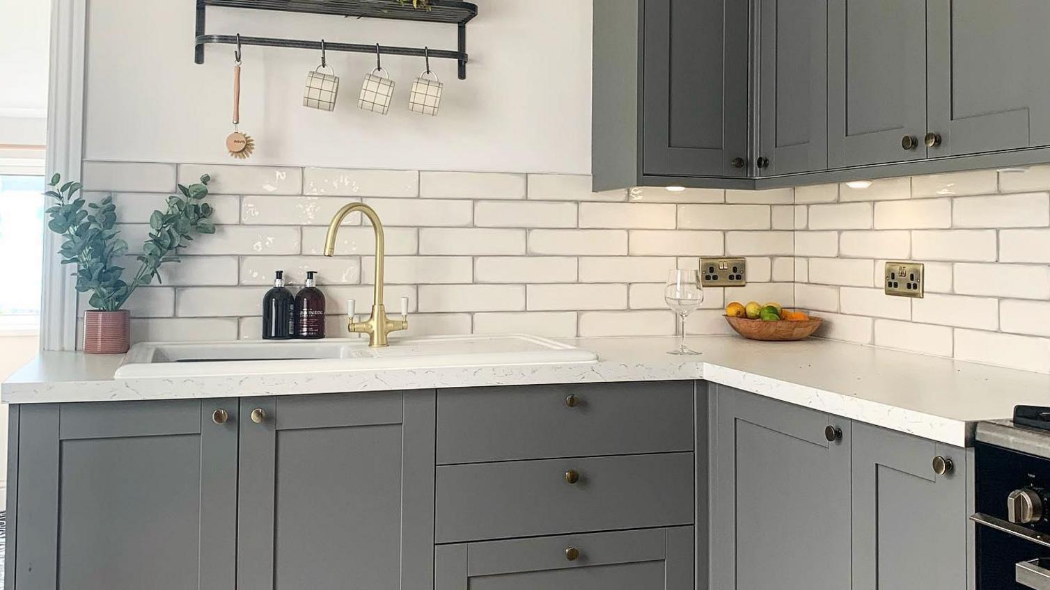 A grey shaker kitchen from Hwodens in a bright white kitchen with wall tiling