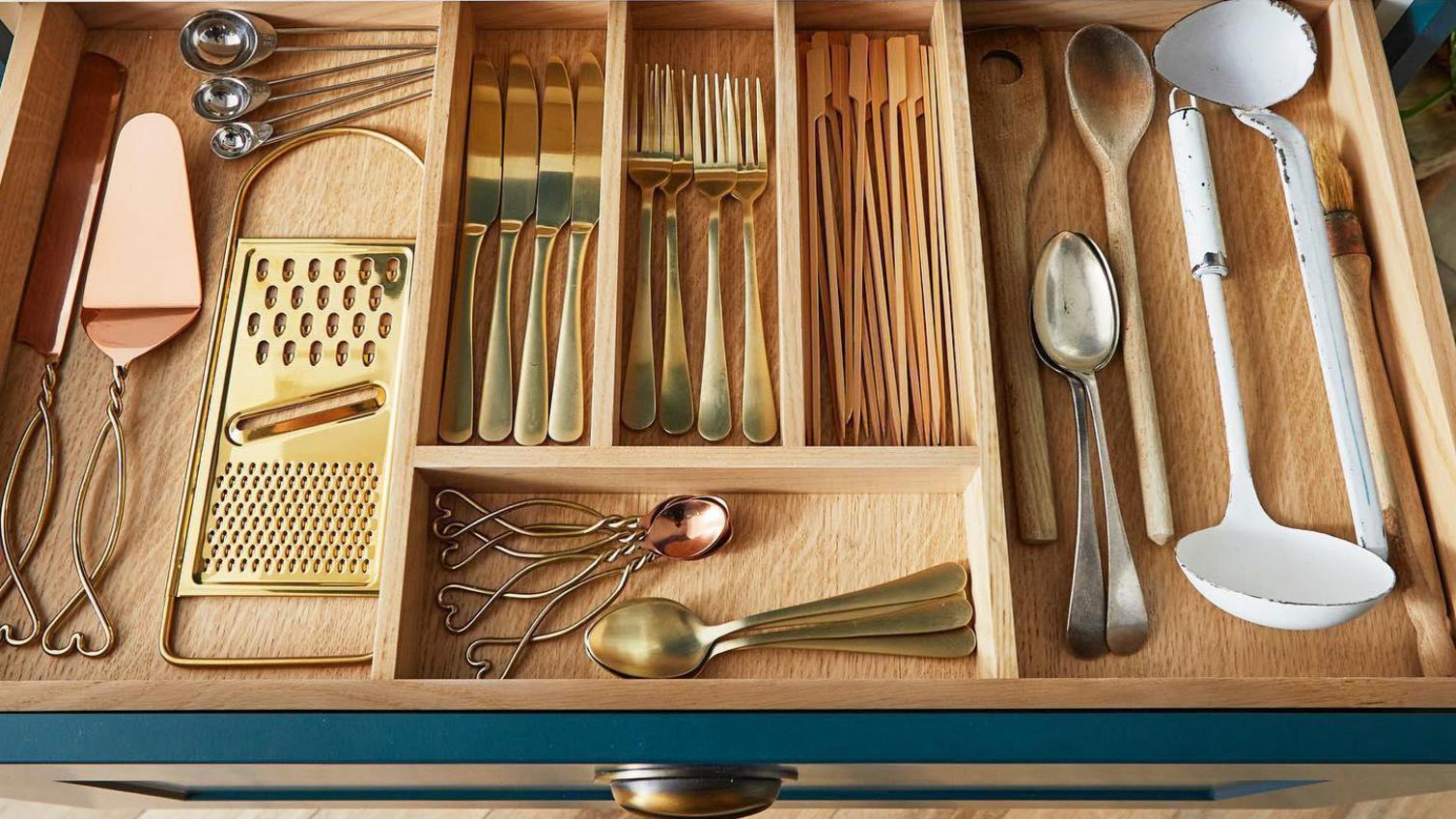 A wooden tray and nearly arranged cutlery inside a vibrant shaker drawer