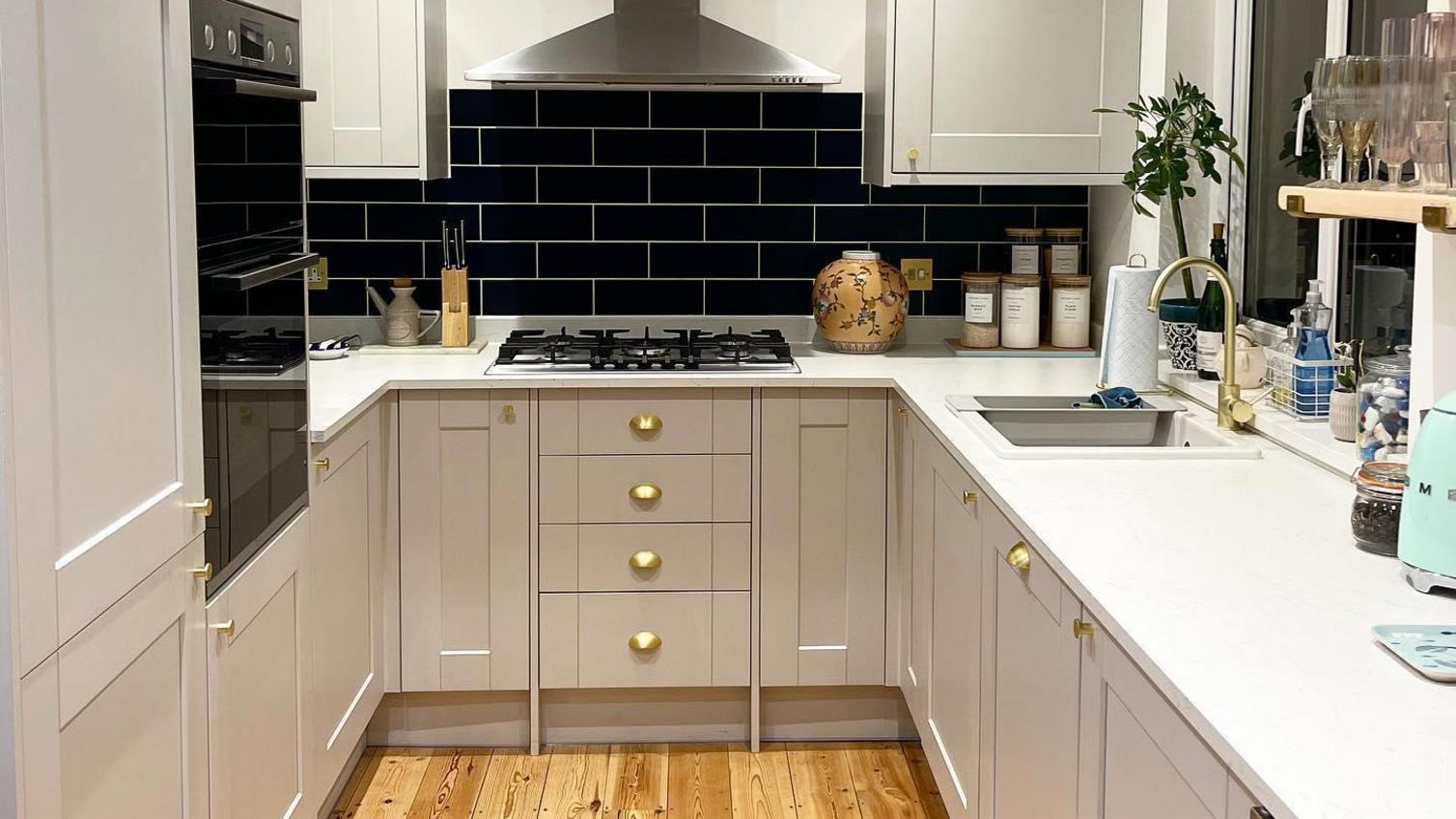 A neutral grey shaker kitchen accented with bright metallic cabinet cup handles