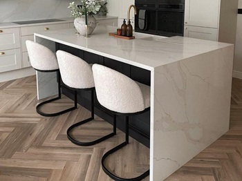 Shaker kitchen island ideas featuring a bespoke quartz workop, herringbone flooring, and a white shaker units.