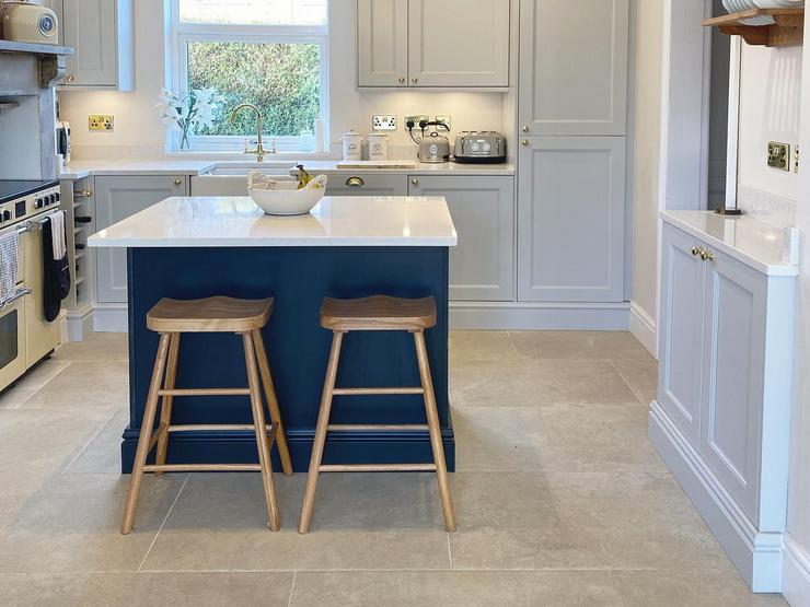 Shaker Kitchen Island idea with blue and grey units, white worktops, stone flooring, and decorative plinths.