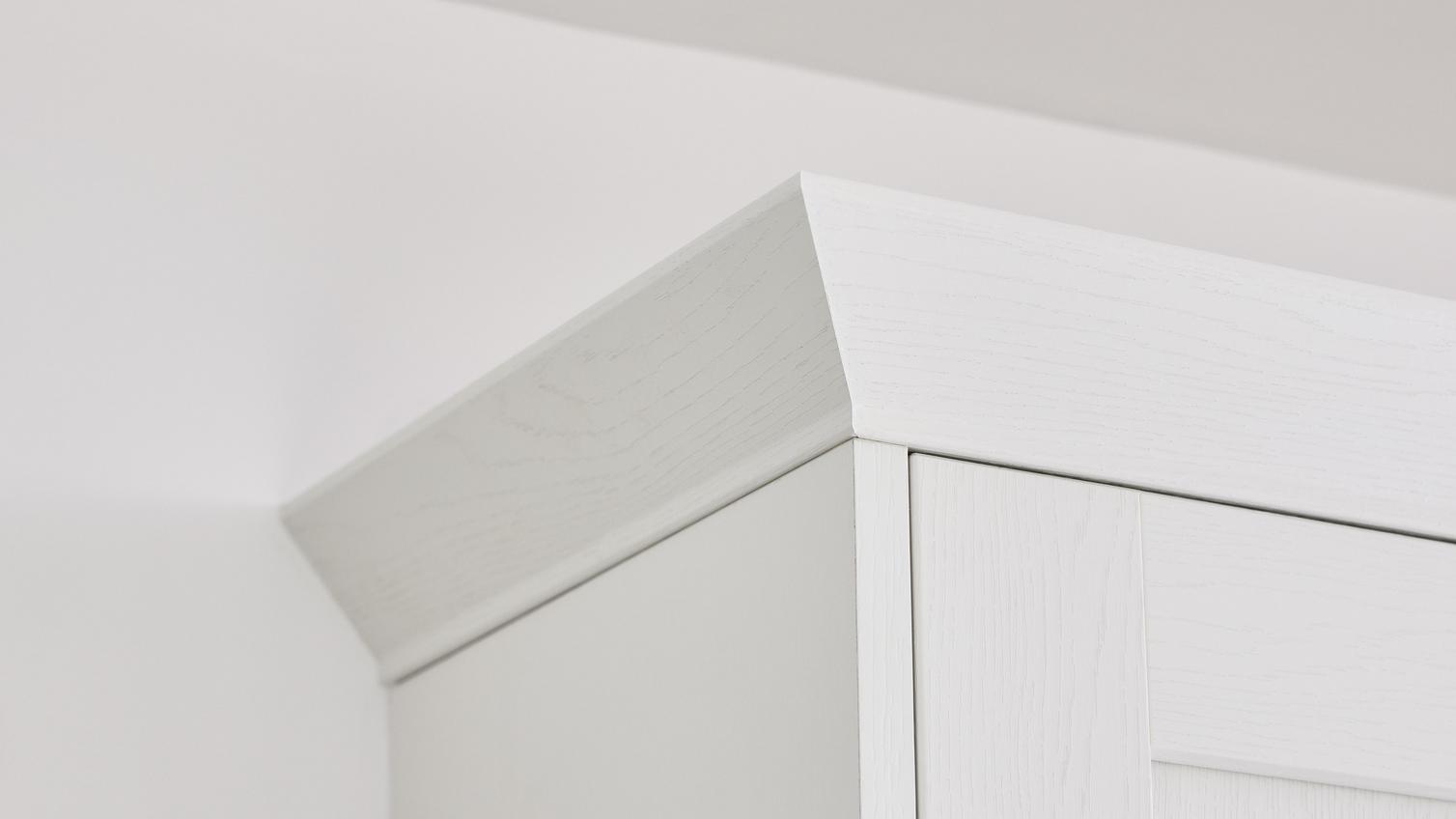 A curved white cornice on top of a white Howden kitchen