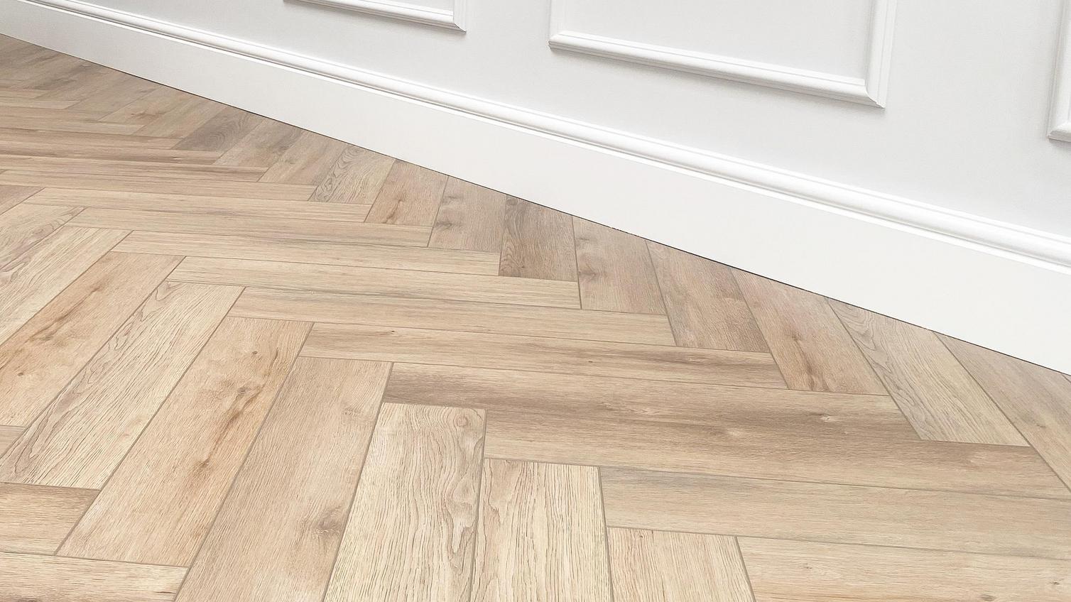 Herringbone laminate flooring in a bright, white bedroom space