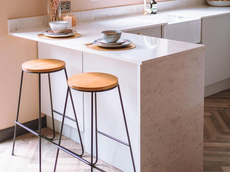 White quartz breakfast bar with marble worktop and brown bar stools