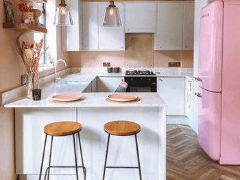 Grey slab kitchen with white quartz worktop, brass handles, and breakfast bar