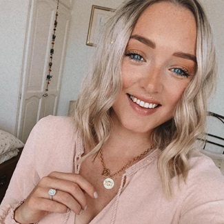 Caucasian women with blonde wavy hair, wearing a blush pink blouse