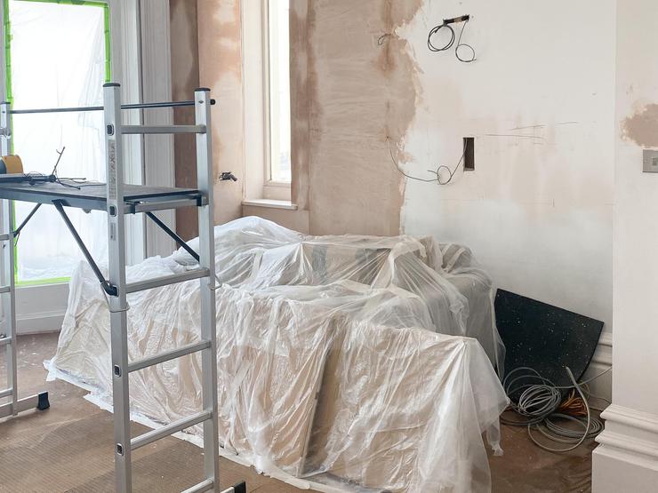 Flat renovation with bare walls, plaster, covered furniture.