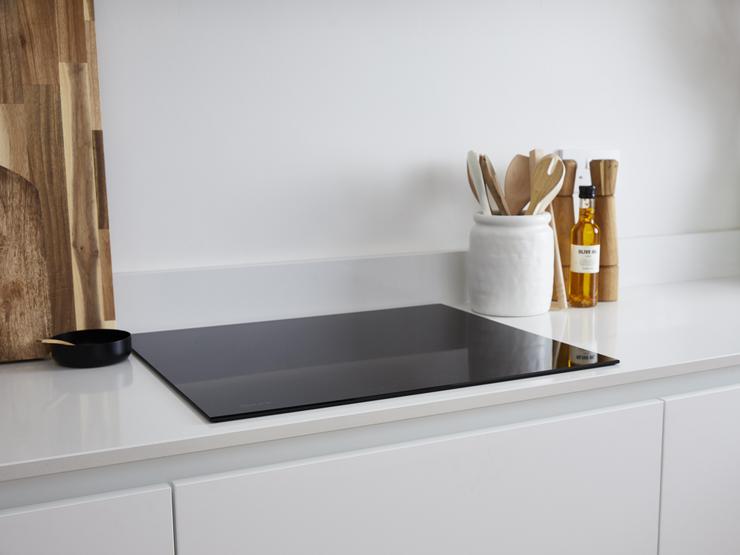 A black induction hob fitted flush to a white quartz worktop with a glossy finish and square-edge profile.