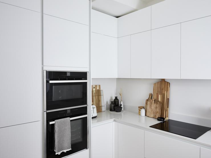 A white appliance tower which includes a black built-in double oven.
