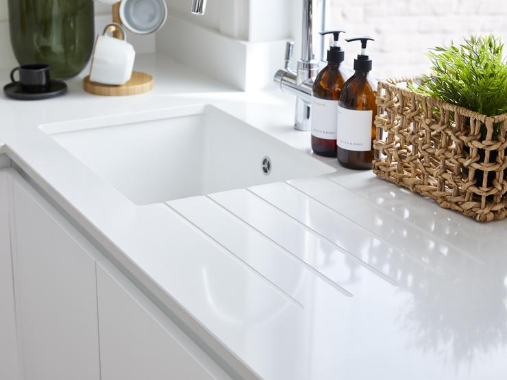 White flossy quartz worktop with a square-edged profile. Has a custom drainer grooves and a white undermount installed in it.