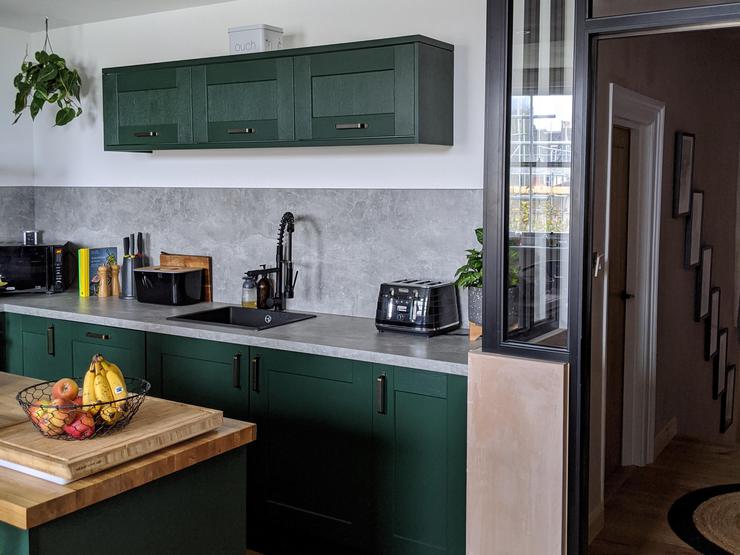 Green shaker kitchen idea in an island layout, with oak effect worktops and a grey concrete worktop and matching backboard.