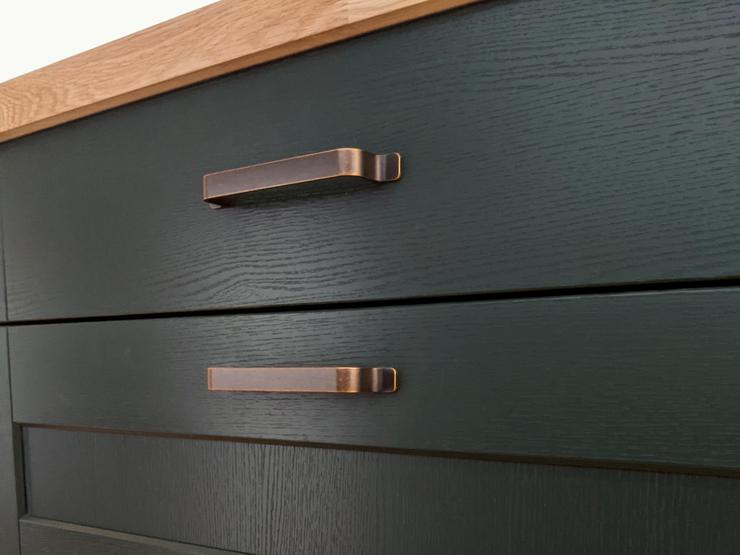 Green shaker kitchen drawers, in a set of three, with antique brass bar handles.