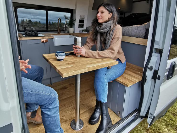 Campervan kitchen with open door and dining table set up