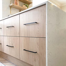 Bank of oak effect slab drawers with black handles