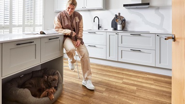 Millie Bright sitting on a breakfast bar with a marble-effect quartz worktop, two storage drawers, and black bar handles.