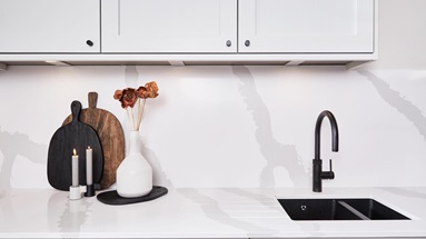 A dove-grey kitchen featuring white, quartz worktops and backboards with a marble-effect pattern for a luxurious look.