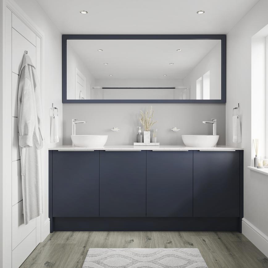 Small bathroom with navy base cabinets and trimline handles. Includes grey-oak flooring, white worktops and two white basins.