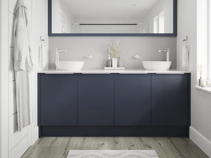 Small bathroom with navy base cabinets and trimline handles. Includes grey-oak flooring, white worktops and two white basins.