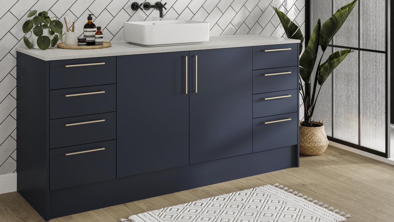 Compact bathroom with navy, slab doors. Contains a large vanity unit, four drawer unit, brass bar handles and open shelving.