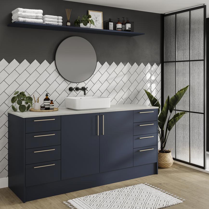 Compact bathroom with navy, slab doors. Contains a large vanity unit, four drawer unit, brass bar handles and open shelving.