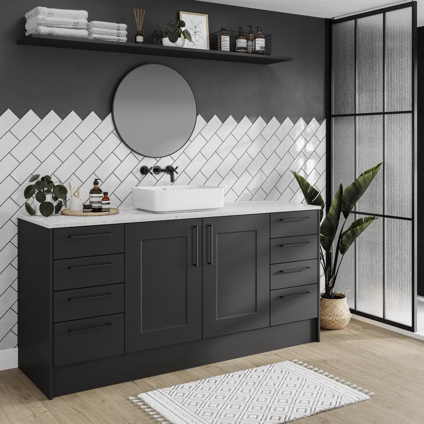 Black shaker cupboard doors in a compact bathroom. Has white metro tiles, a white worktop, a round mirror, and an oak floor.