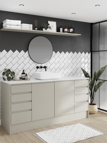 Modern integrated handle bathroom with matt sandstone cupboard doors, drawers, white worktop and tiles, and a black tap.