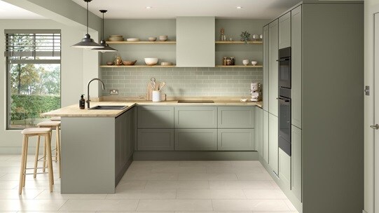 A reed green, modern shaker kitchen from the Frome handleless collection. It has a timber worktop and a u-shaped layout