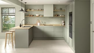 A reed green, modern shaker kitchen from the Frome handleless collection. It has a timber worktop and a u-shaped layout