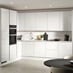 A white, modern kitchen in a gloss finish and handleless cabinets. It is in an l-shaped layout and stone-effect flooring.